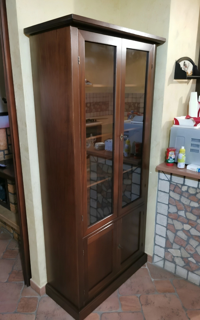 Vetrina espositiva classica in legno noce con ante in vetro e bicchieri di cristallo all'interno