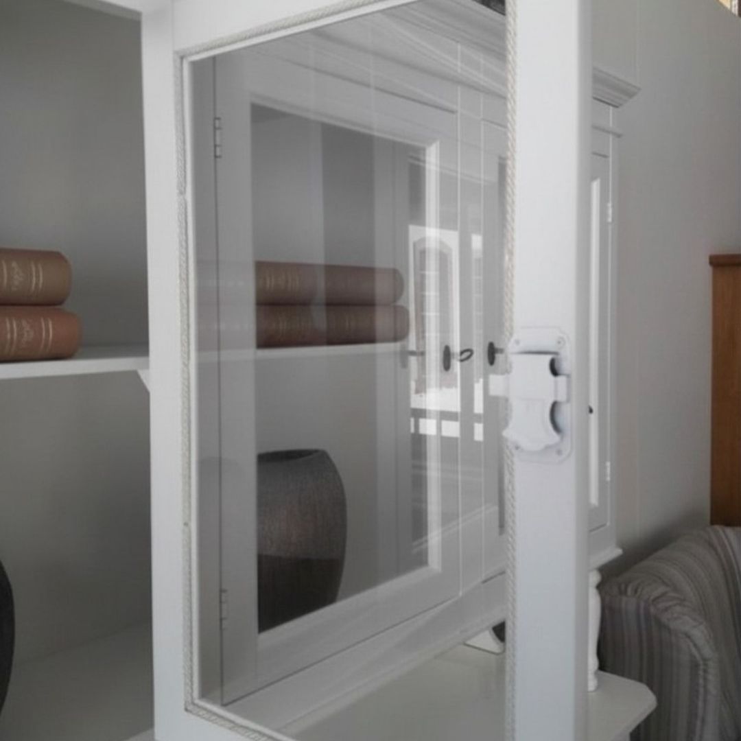 Dettaglio delle ante in vetro della vetrina, con chiusura classica e struttura in legno bianco opaco.