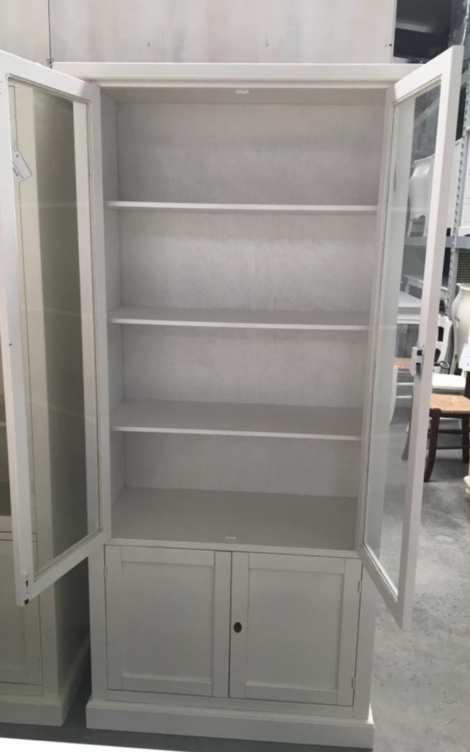 Vetrina in legno bianco opaco con ante a vetro aperte e vano inferiore chiuso, stile Arte Povera.