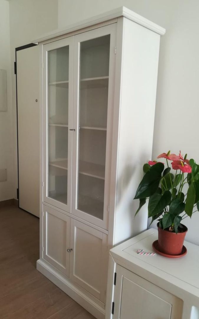 Vetrina in legno bianco aperta, che mostra la struttura interna con ripiani e spazio di archiviazione inferiore.