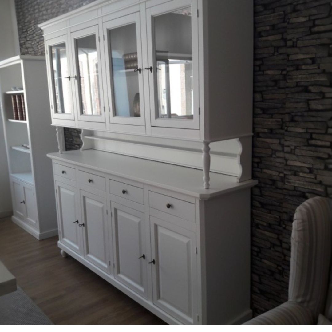 Vetrina in legno bianco opaco accanto a una libreria nello stesso stile.