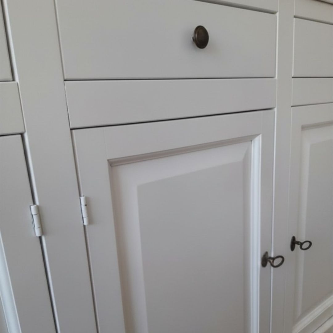 Particolare della struttura e delle colonnine decorative di una vetrina in legno bianco.