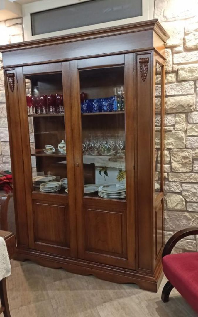 Vetrina in legno finitura Bassano con vetri, utilizzata come espositore per piatti e cristalleria in una zona giorno.