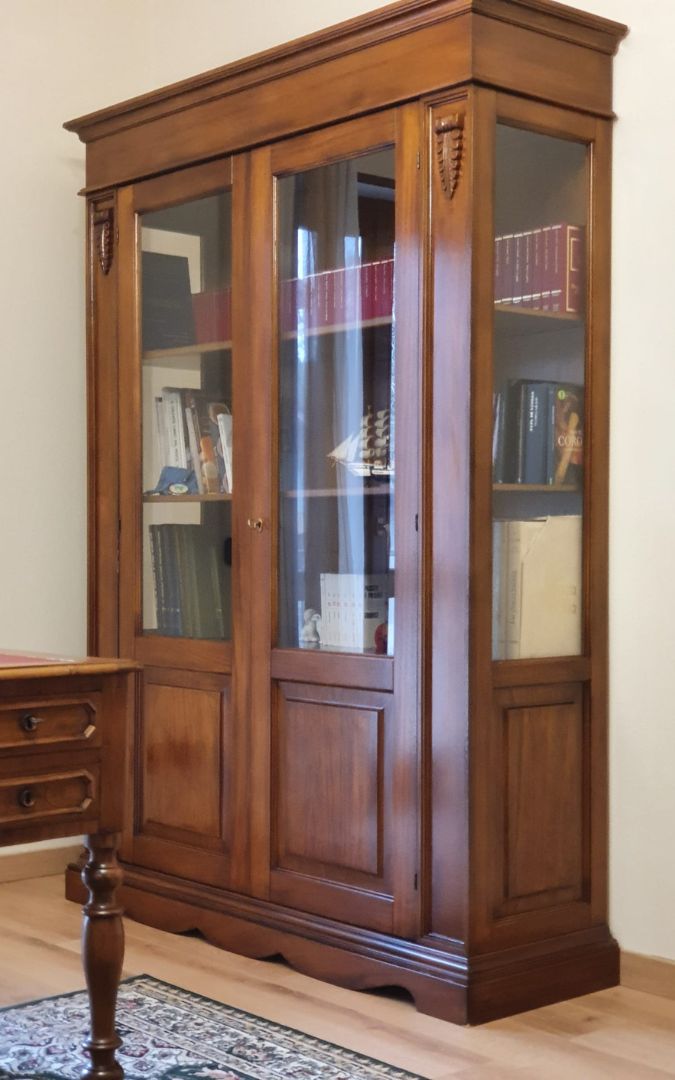 Vetrina libreria in legno noce scuro con ante vetrate e ripiani, perfetta per uno studio classico o un salotto.