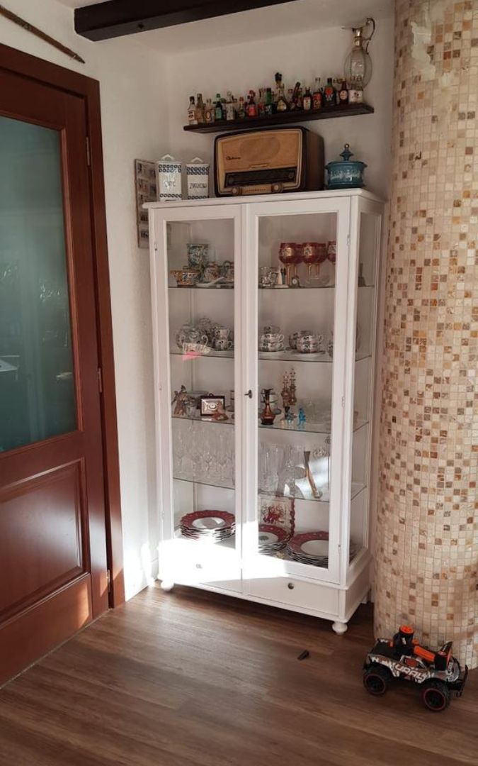Vetrina da salotto in legno bianco opaco, stile arte povera, utilizzata come cristalliera.
