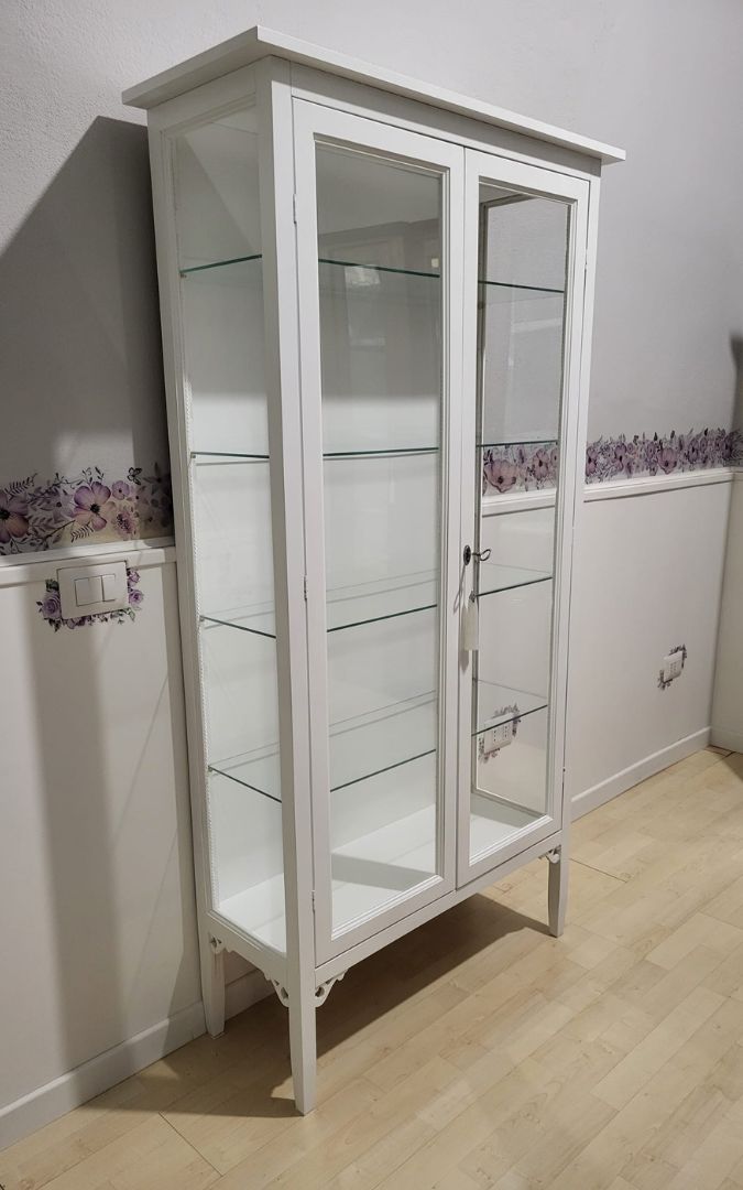 Vetrina in legno classica, due ante in vetro, finitura bianco opaco, inserita in ambiente domestico.