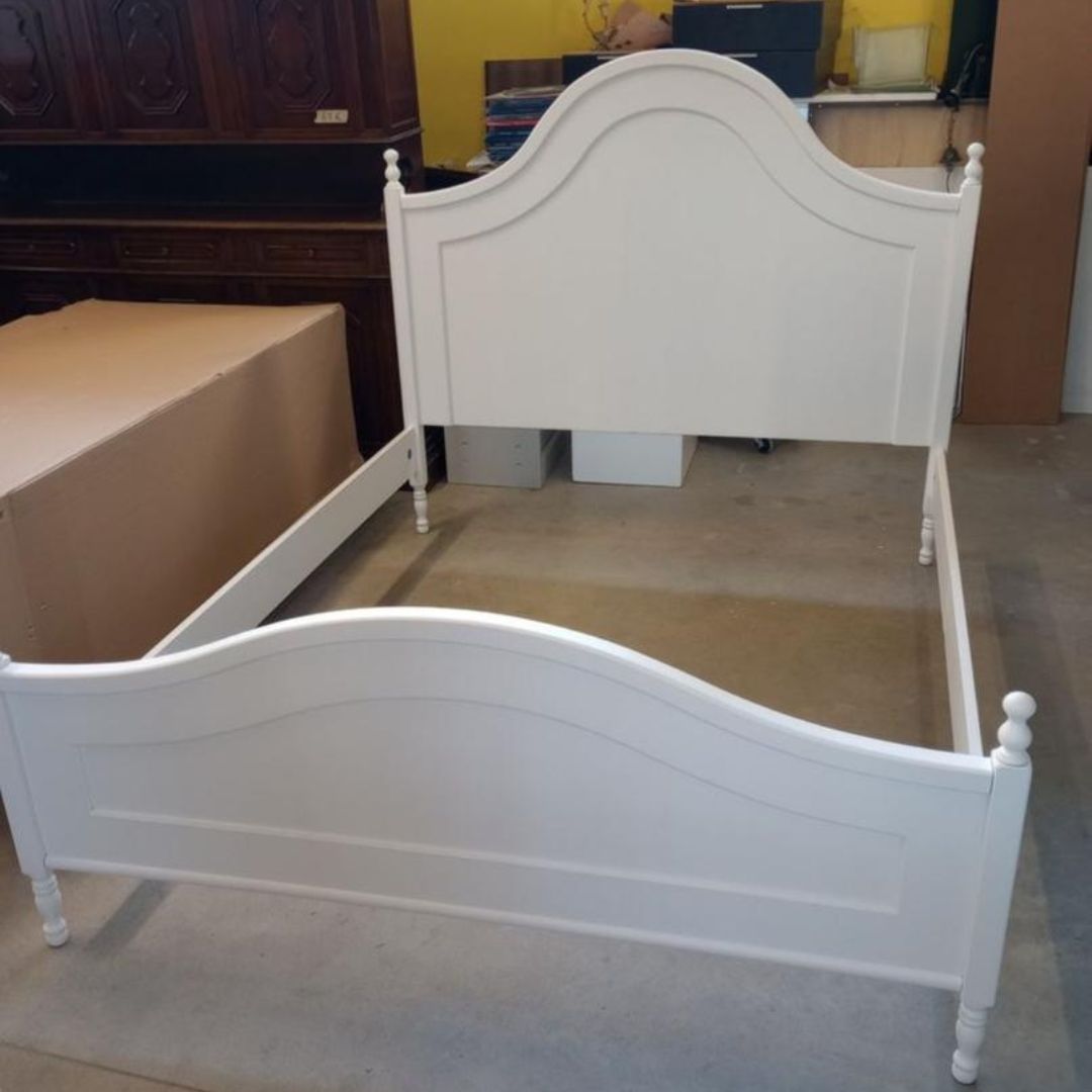 Letto matrimoniale bianco in stile Arte Povera inserito in una camera da letto rustica con pareti in pietra.