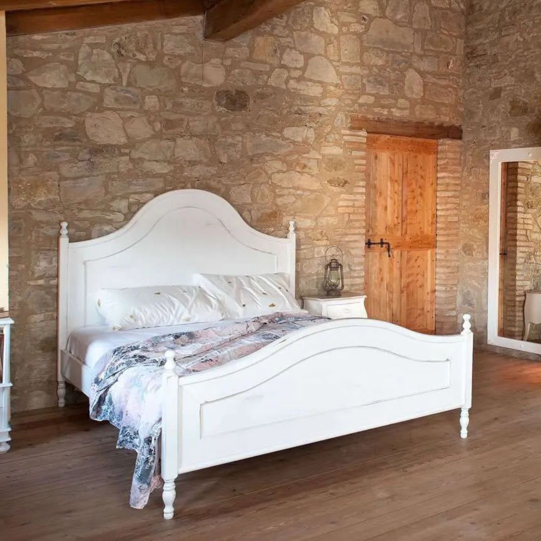 Dettaglio della testiera sagomata di un letto matrimoniale bianco in legno massello.
