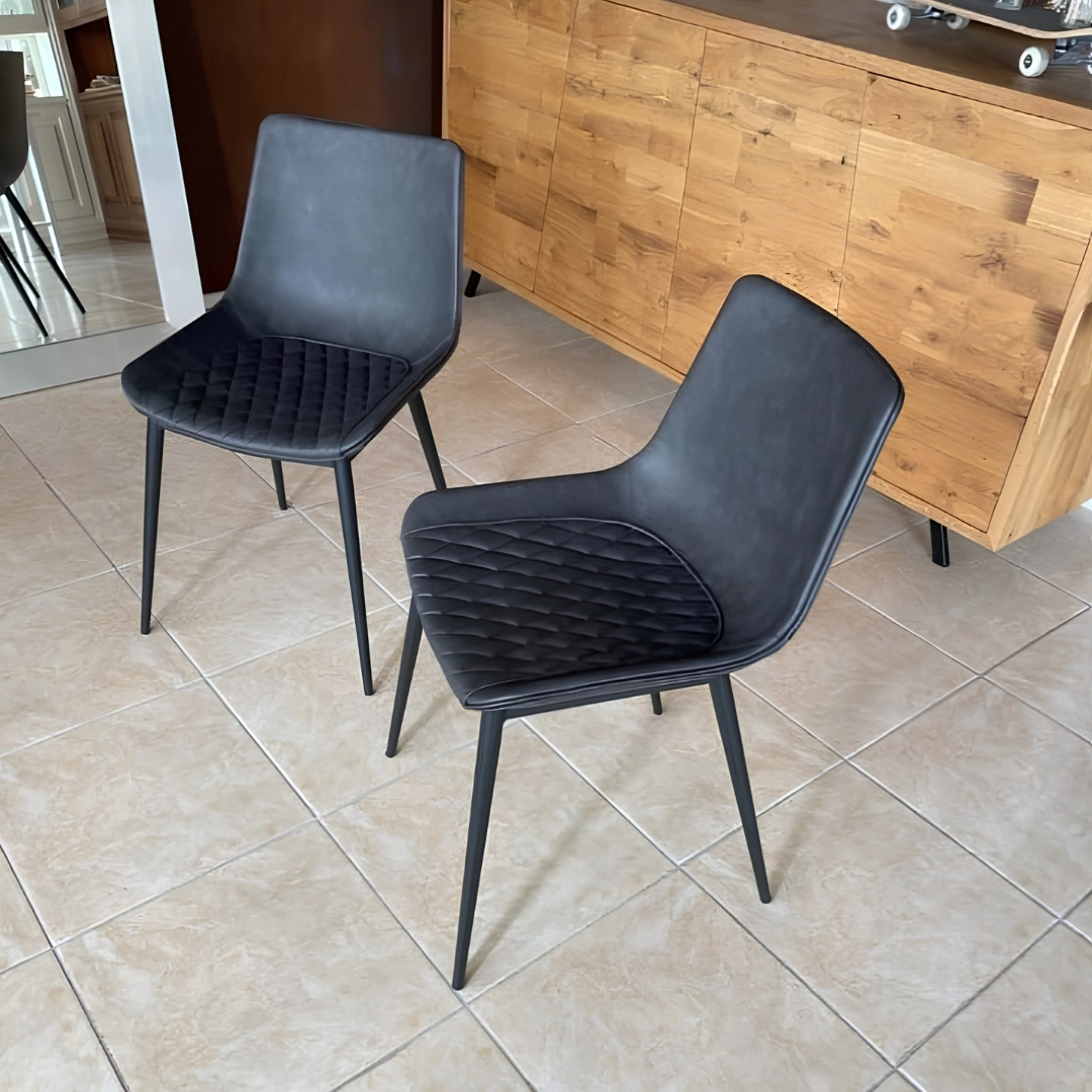 Set di 2 sedie moderne nere imbottite posizionate in una sala da pranzo vicino a un mobile in legno