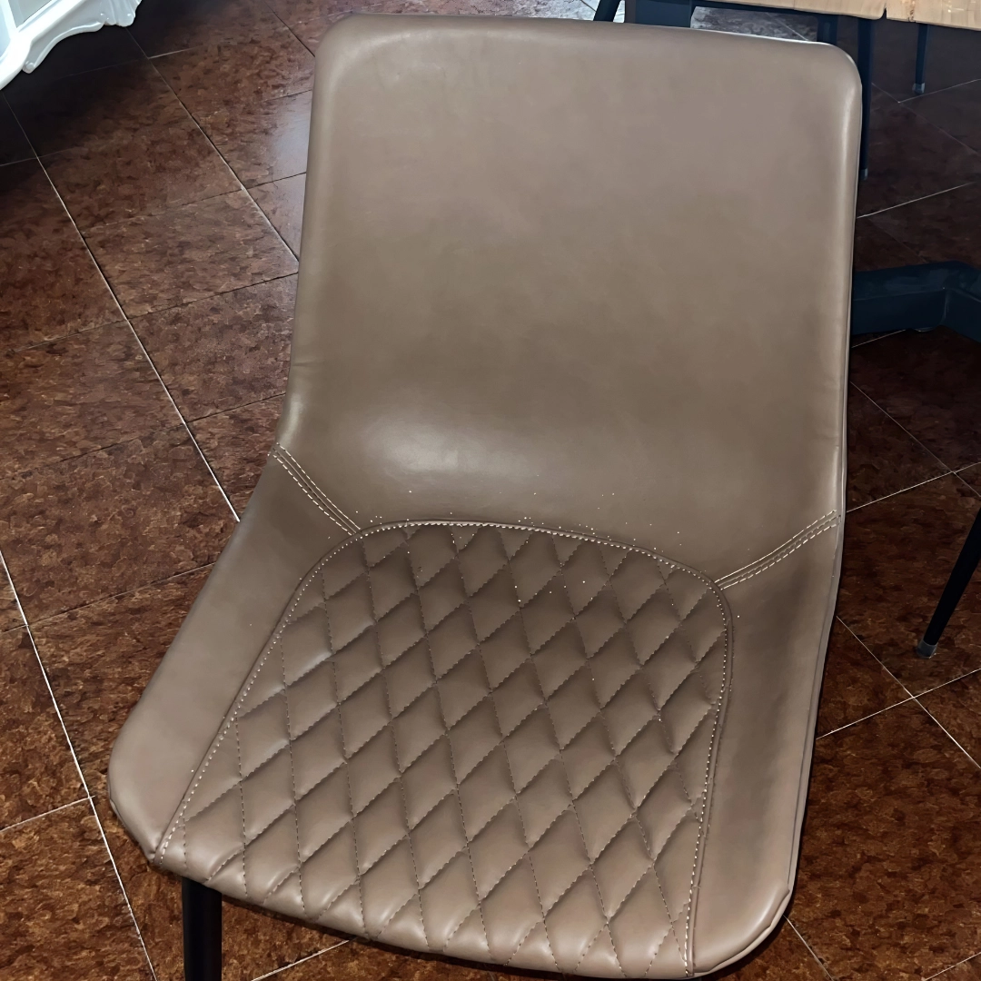 Vista frontale di sedia moderna imbottita color tortora con lavorazione trapuntata a rombi sulla seduta