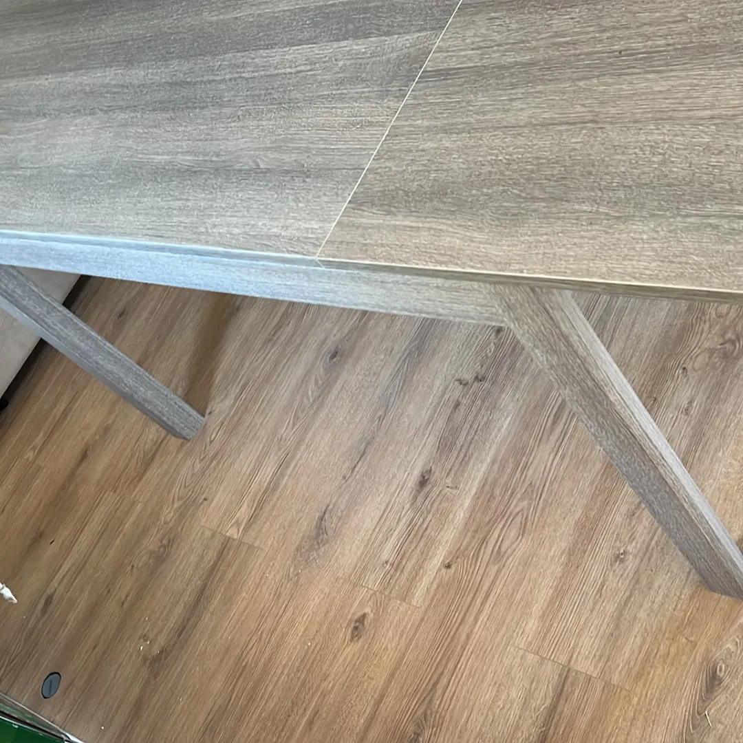 Primo piano del design e della struttura del tavolo allungabile in legno bianco frassinato e tortora, per vedere la qualità della finitura.