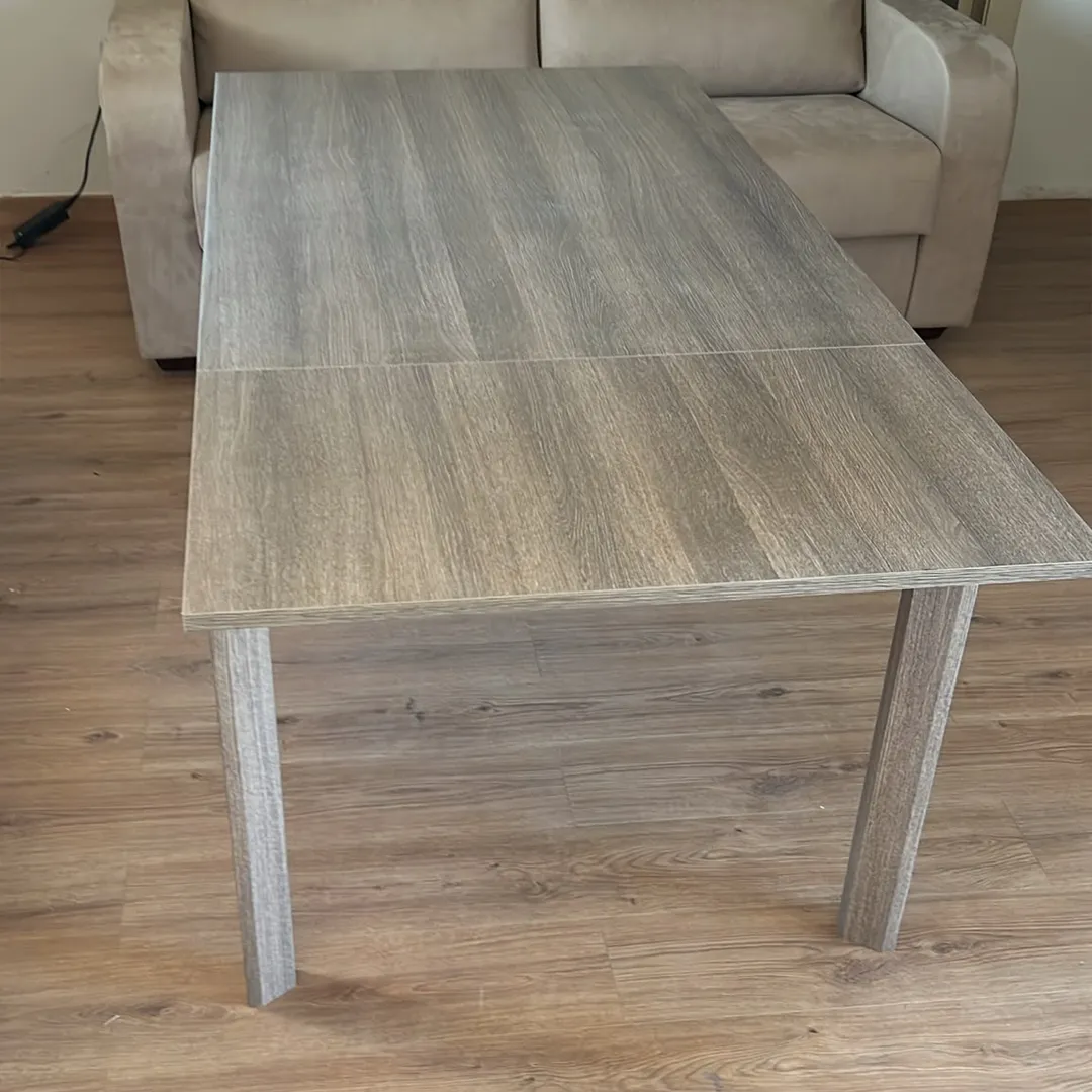 Vista frontale di un tavolo allungabile in legno con eleganti venature bianco frassinato e tonalità tortora, perfetto per ambienti moderni.