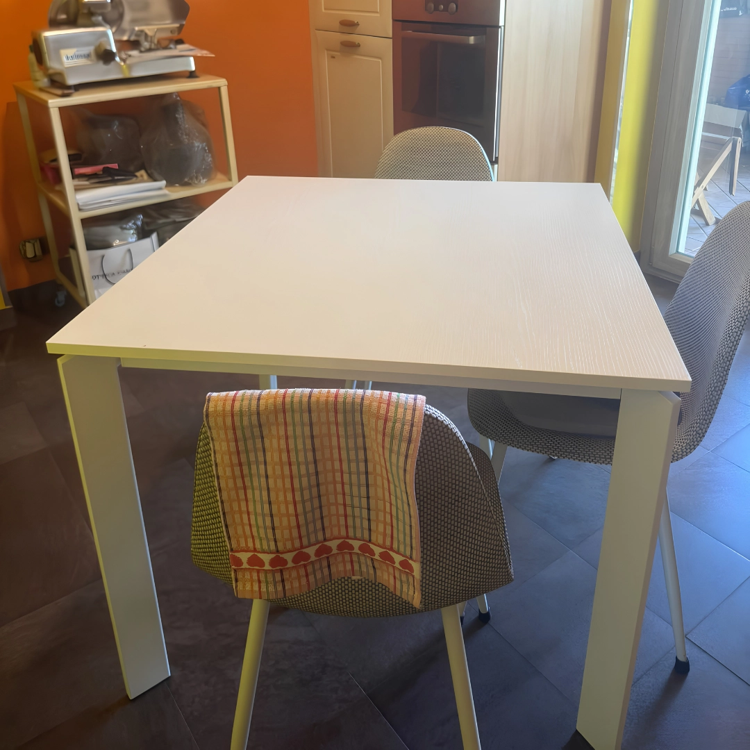 Primo piano tavolo quadrato bianco con sedie rivestite in tessuto grigio - Marca Design Shop