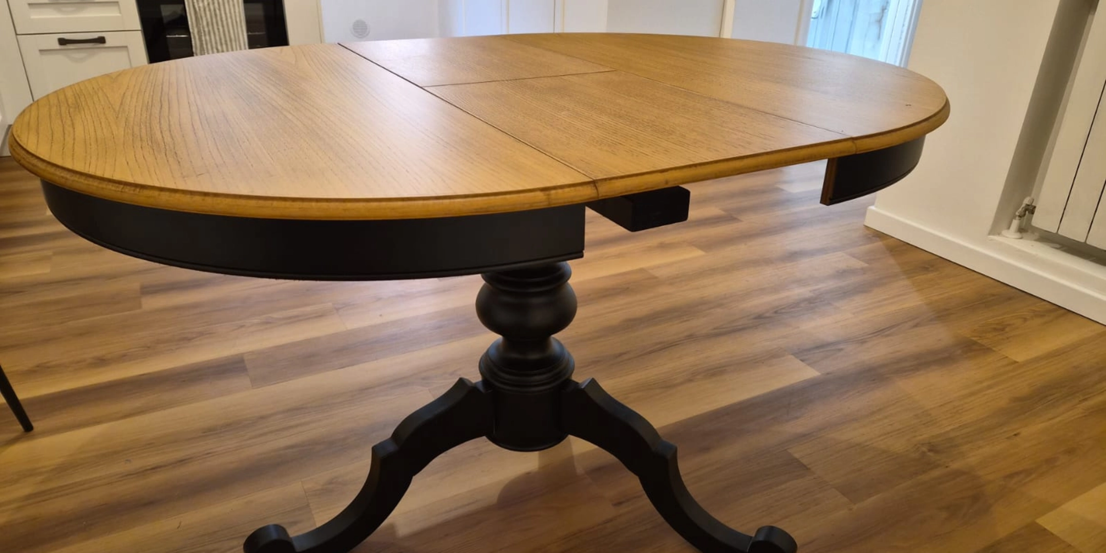 Vista angolare tavolo rotondo allungabile piano legno chiaro e base nera - Marca Design Shop
