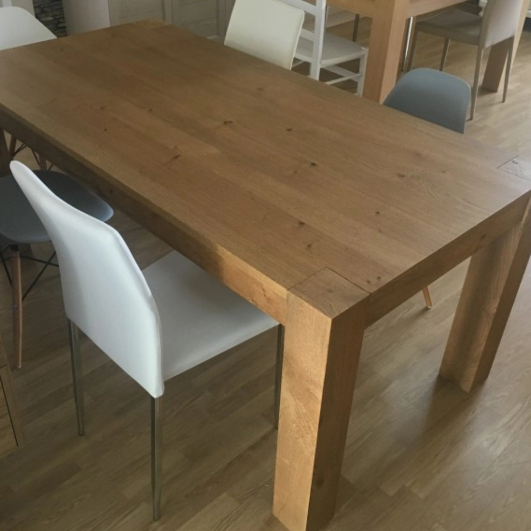 Angolo del tavolo moderno in rovere Marca Design Shop con gambe squadrate, abbinato a sedie di design miste in un salotto con parquet.