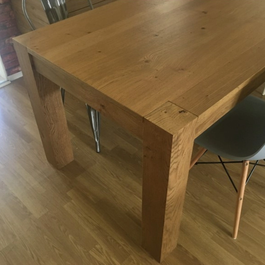 Primo piano della giunzione dell'angolo del tavolo Marca Design Shop in rovere naturale, che evidenzia la qualità del legno massello e la finitura.