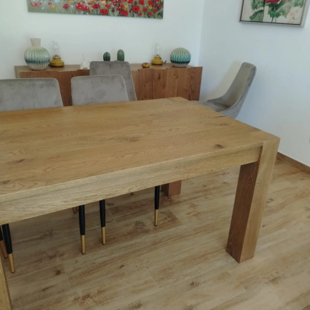 Vista laterale del tavolo rovere Marca Design Shop, con enfasi sulla robustezza delle gambe e sulla continuità del disegno del legno lungo il bordo.