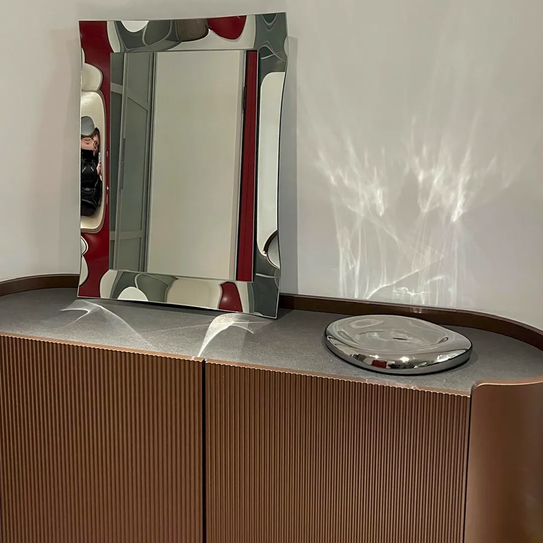 Specchiera moderna rettangolare con cornice sagomata argento su madia di design.