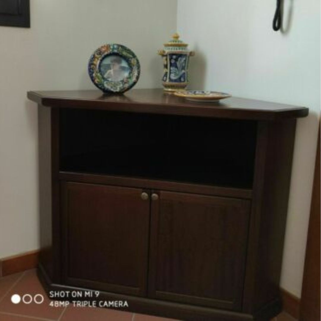 Mobile porta TV ad angolo in stile classico color noce, con vano aperto e antine chiuse.