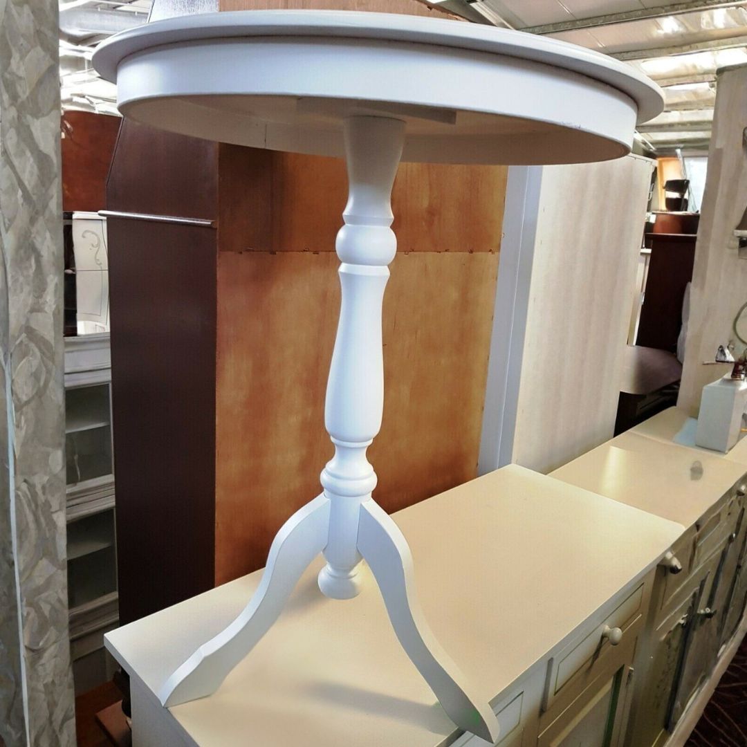 Dettaglio della base lavorata del tavolino rotondo bianco con gamba centrale.