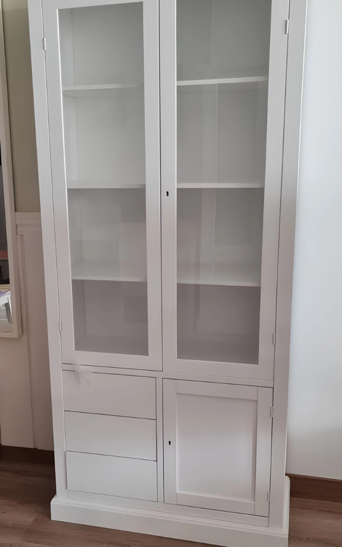 Vetrina in legno laccato bianco con ante in vetro, 3 cassetti sul lato sinistro e una porta cieca a destra