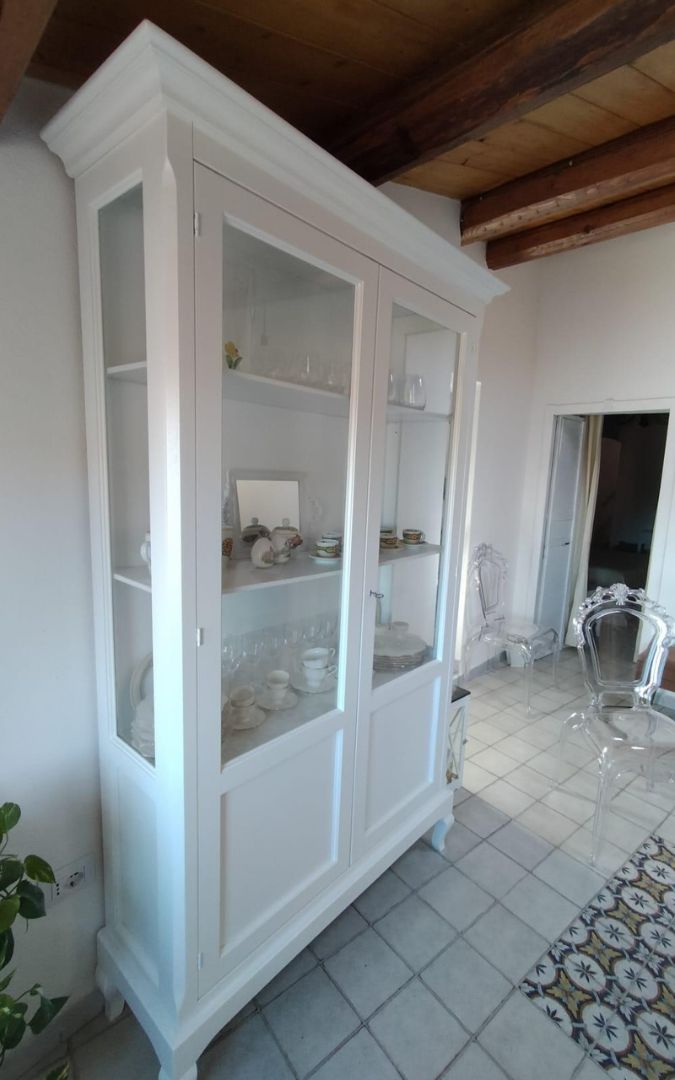 Mobile cristalliera stile Arte Povera in legno bianco, vista ravvicinata dei ripiani interni con servizio da tè.