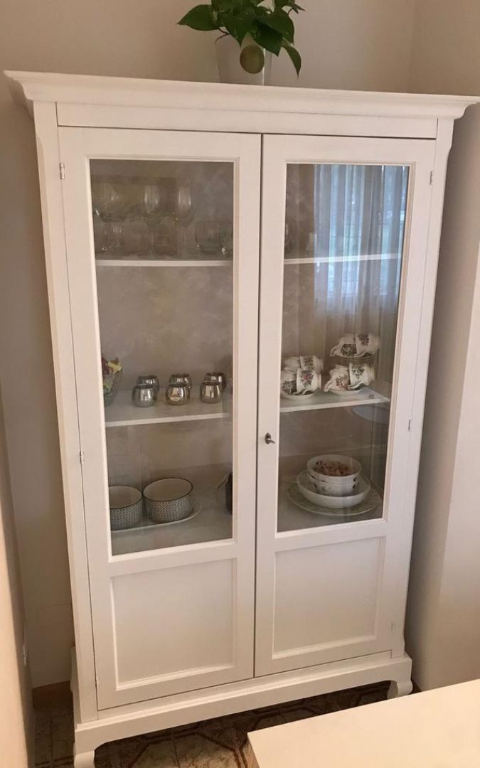 Vetrina classica bianca con ripiani utilizzati per riporre tessili e biancheria di casa.