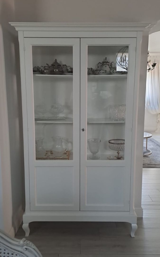 Dettaglio mobile cristalliera bianco stile classico con ante in vetro.