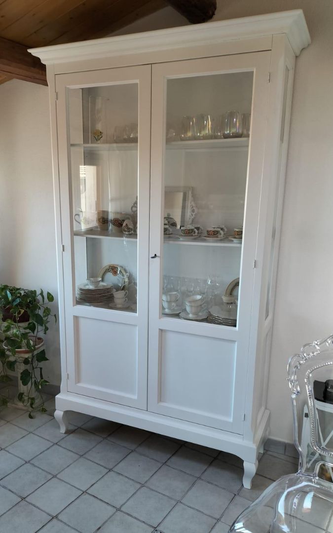 Mobile vetrina bianco stile Arte Povera in un ambiente living con sedie trasparenti.