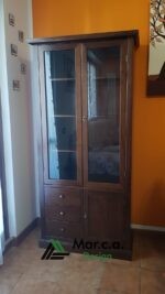 Vetrina in legno massello stile arte povera. Con Finitura Bassano. Dotata di 2 porte vetrate, 3 cassetti e 1 anta.